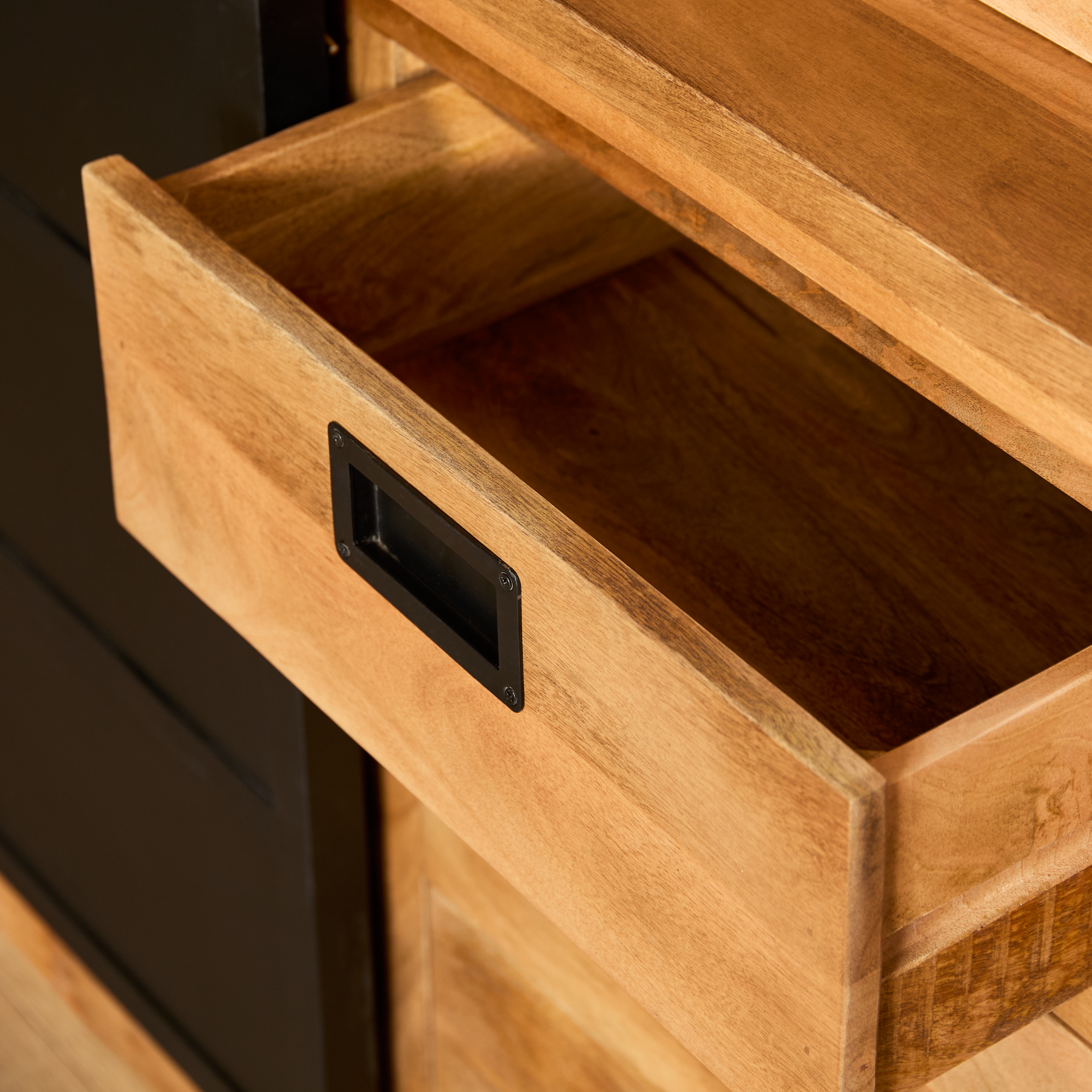 Een close-up van de Nashville Vitrinekast | 120 cm toont een gedeeltelijk geopende houten lade met een zwart handvat, waardoor de lege binnenkant zichtbaar wordt tegen de bijpassende kast.