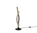 De TRIO Tafellamp Blaze is een moderne, sculpturale tafellamp met twee in elkaar verstrengelde, golvende LED-lichtstroken - een gouden, een zwarte - op een ronde, zwarte voet met een zichtbaar netsnoer.