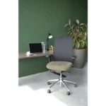 De Workliving Nora Mesh Groen Regain ergonomische bureaustoel (NEN1335) met een groene zitting en zwarte rugleuning staat voor een zwevend bureau met een laptop, glas water, lamp en potplant tegen een donkergroene muur.