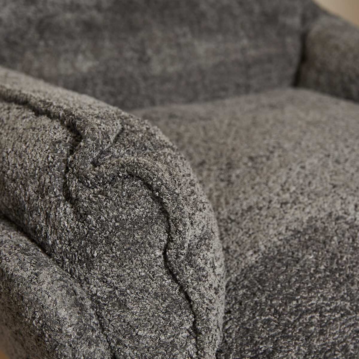 Close-up van de gestructureerde, gekrulde armleuning en het zitkussen van de Fauteuil Vera Dark Grey, met de nadruk op de zachte pluche stof en de gedetailleerde stiksels.