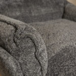Close-up van de gestructureerde, gekrulde armleuning en het zitkussen van de Fauteuil Vera Dark Grey, met de nadruk op de zachte pluche stof en de gedetailleerde stiksels.