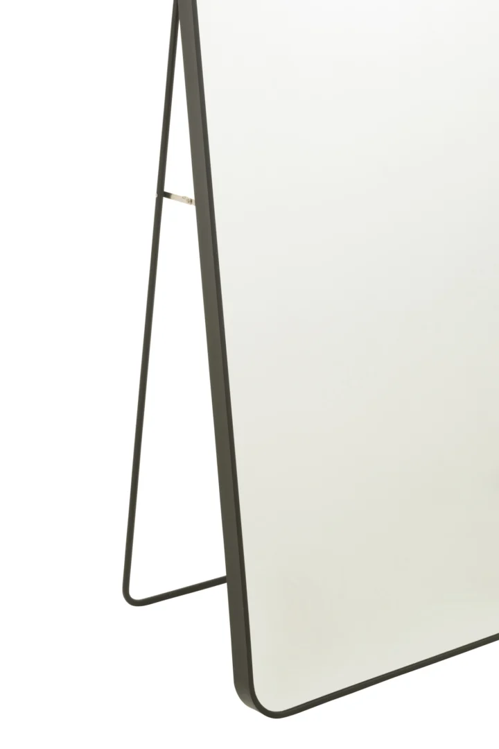 Een close-up van de onderste hoek van de Mirror On Foot Rectangle Gl/Met Bl, een vrijstaande rechthoekige spiegel met een zwart metalen frame en dunne steunpoten.