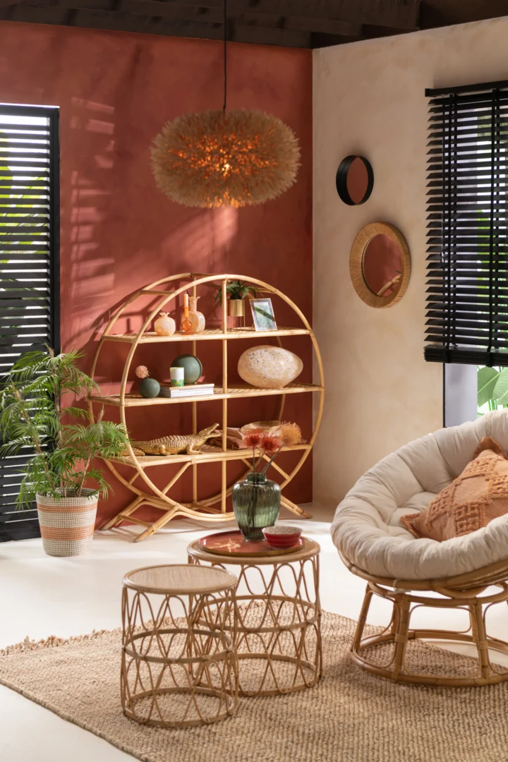 In een gezellige, moderne woonkamer ligt het Vloerkleed Havana Poly Naturel/Wit Klein met een ronde rotan stoel, ronde planken, rieten tafels, kamerplanten en decor. Aardetinten en natuurlijke texturen versterken de ontspannen sfeer.