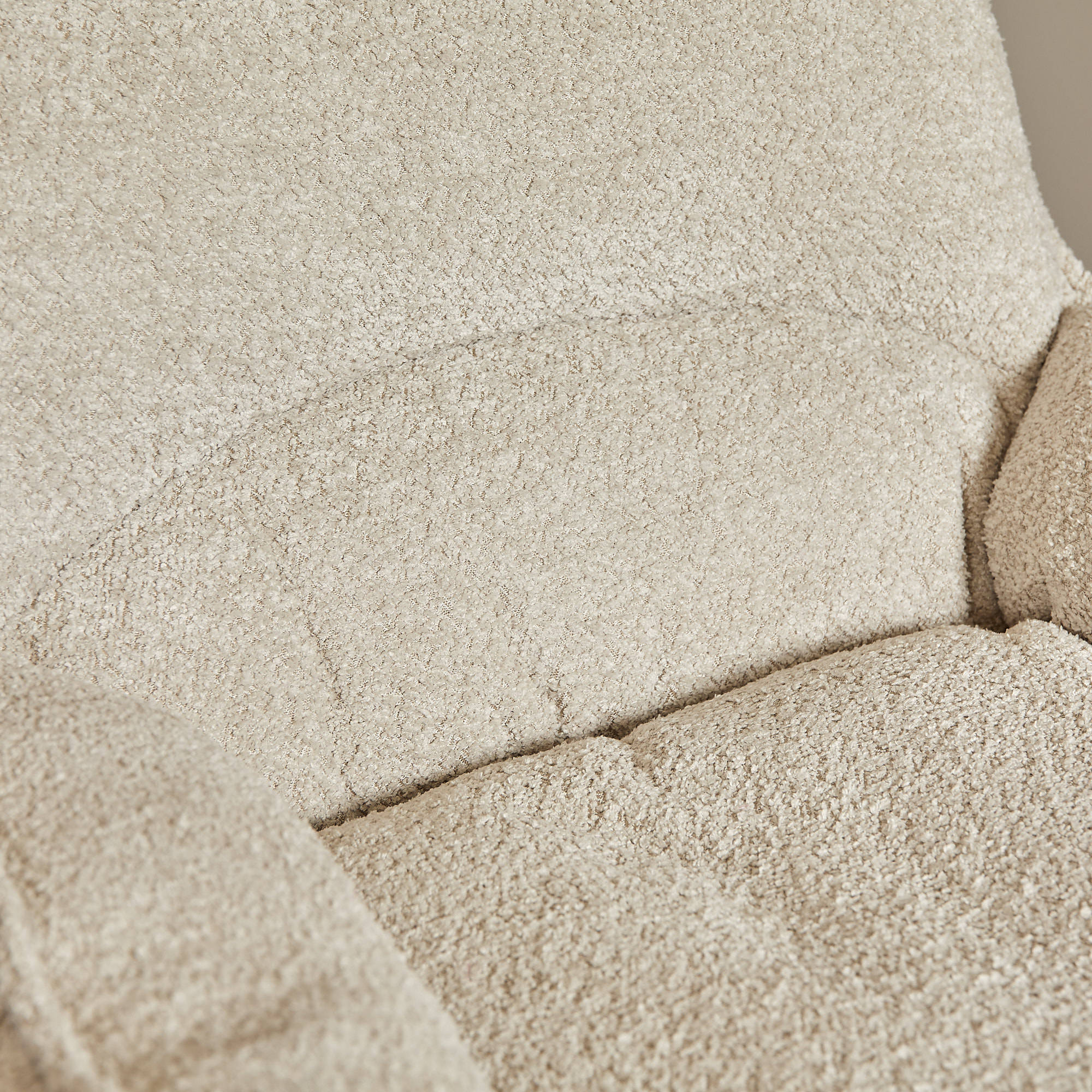 Close-up van de Fauteuil Vera Off White, een beige gestoffeerde stoel met zachte vulling op de zitting en rugleuning.