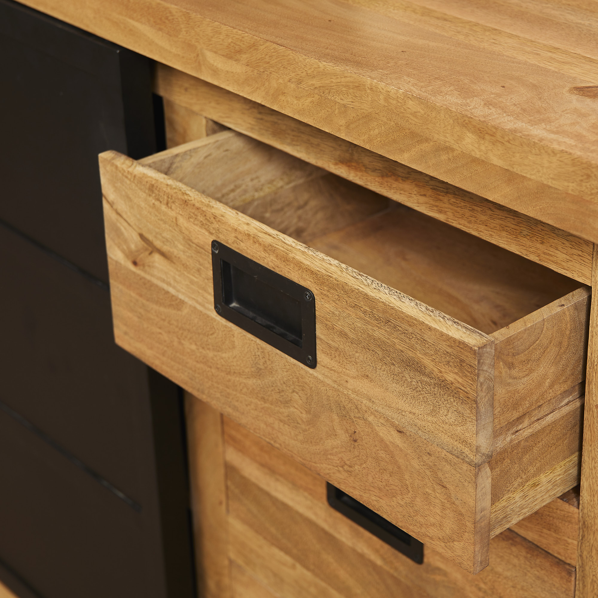 Een close-up van de Nashville Dressoir | 160 cm toont een gedeeltelijk open lade met een zwart metalen labelhouderhandvat. De kast heeft een natuurlijke houten afwerking met zichtbare nerfpatronen en een leeg interieur.