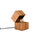De TRIO Tafellamp TREASURE is een moderne houten tafellamp met twee op elkaar gestapelde kubussen. De bovenste kubus is gekanteld om een vintage gloeilamp binnenin te onthullen en een zwart snoer dat uit de achterkant steekt.
