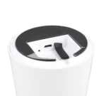 Een close-up van de bovenkant van de REALITY Tafellamp LENNON, een wit cilindervormig apparaat met een zwarte ronde deksel, waarop een USB-poort, indicatielampje en een gebogen zwarte hendel te zien zijn.