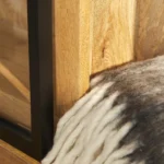 Close-up van de Nashville Vitrinekast | 200 cm met een licht houten plank en zwart metalen frame naast een pluche wit en grijs wollen vloerkleed. Warm zonlicht laat de natuurlijke houtnerf mooi uitkomen.