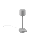 De Reality Tafellamp Fernandez is een moderne, minimalistische tafellamp met een cilindrische witte lampenkap, slanke verticale voet, vierkante voet en een wit netsnoer dat vanaf de voet naar links loopt.