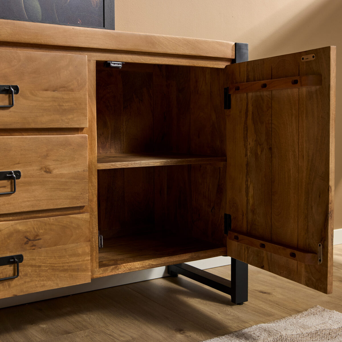 De Dressoir Boaz 200 cm heeft zwarte metalen poten en handgrepen, staat op een lichte houten vloer, met één deur open om een leeg interieur met twee planken te onthullen en drie gesloten lades aan de linkerkant.