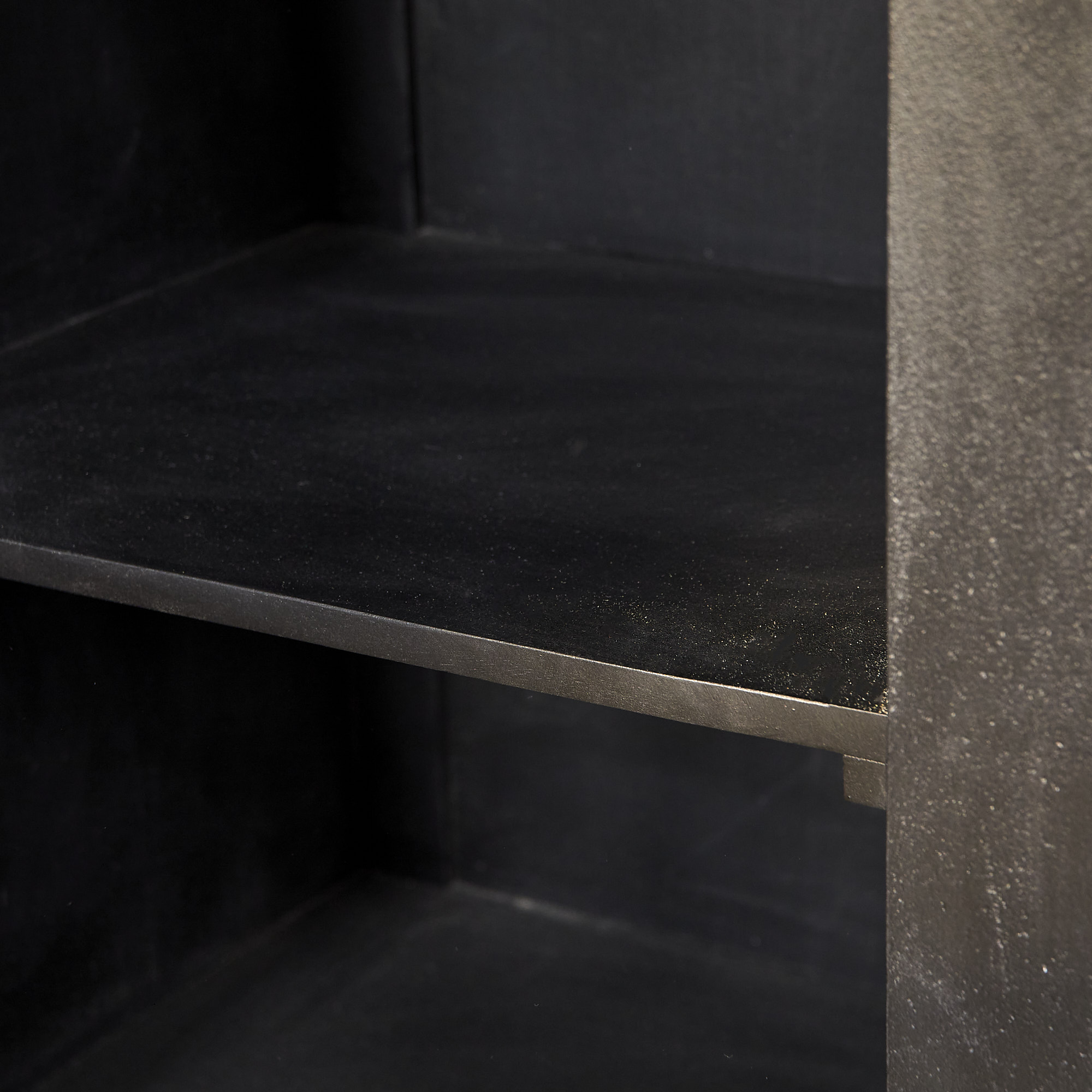 Een close-up van de Dressoir Brussel Black 3 deurs (150 cm), met de nadruk op één plank en de matte, licht gestructureerde zwarte metalen zijpanelen.