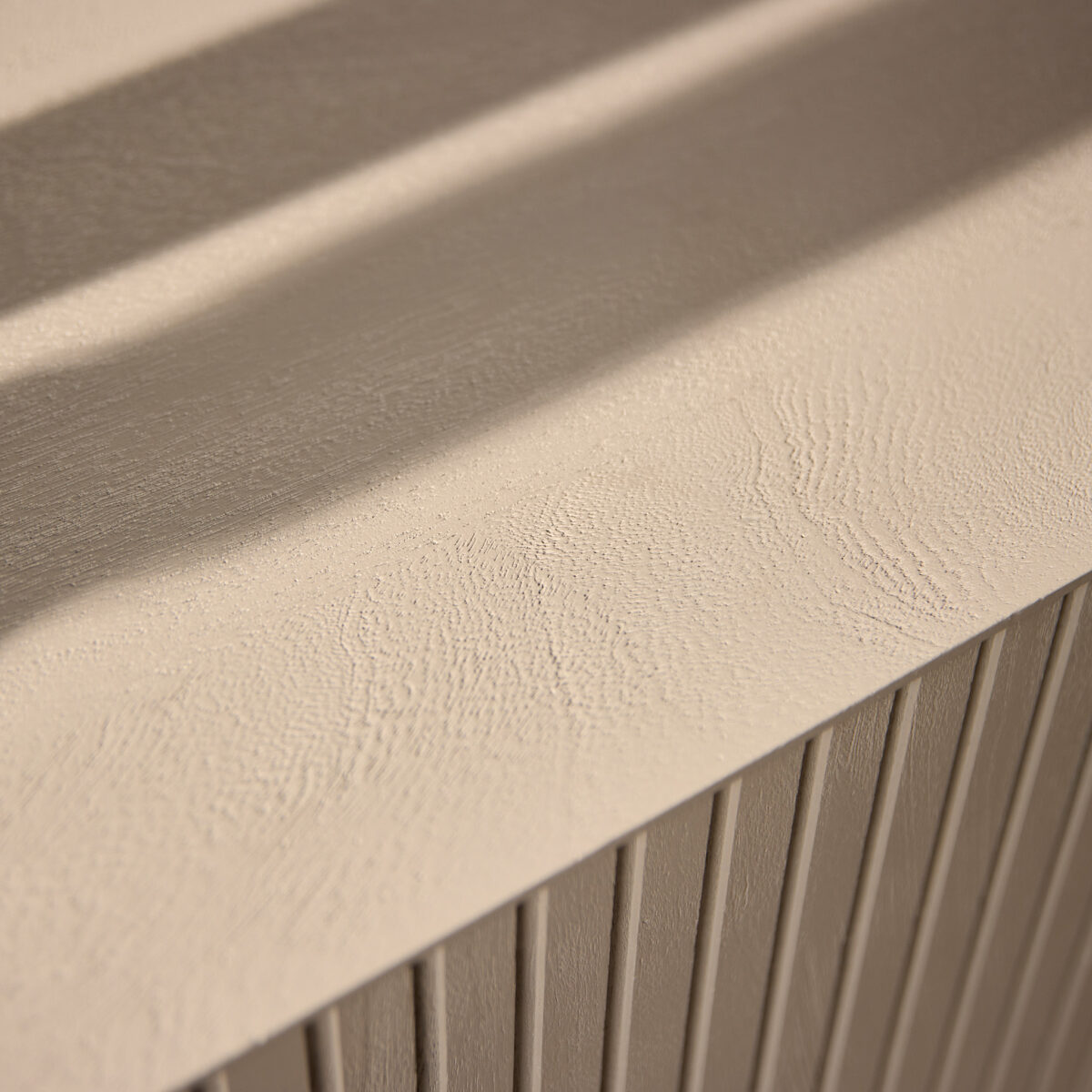 Close-up van de Dressoir Madison Sand | 210 cm, die het beige gestructureerde oppervlak met subtiele golvende patronen en verticale groeven laat zien, met zachte schaduw.