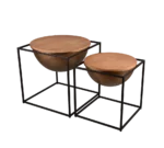 De Mirrors and More Bijzettafel CELLI bestaat uit twee moderne nesttafels van verschillende afmetingen, elk met een rond houten blad, een bronzen komvormig onderstel en een zwart metalen kubusvormig frame, naast elkaar geplaatst.