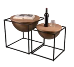 De Mirrors and More Bijzettafel CELLI set bestaat uit twee moderne bijzettafels met houten bladen en zwarte metalen frames - op de grootste staan een open boek en een bril, terwijl op de kleinere een wijnfles en glas passen.