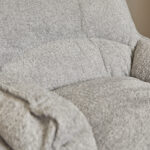 Close-up van de Fauteuil Vera Lichtgrijze fauteuil, met zachte, gestructureerde stof en pluche kussens op de zitting, rugleuning en armleuning.
