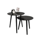 Twee moderne zwarte Mirrors and More Bijzettafel VILANA ronde bijzettafels, de ene hoger en de andere overlappend. Op de hogere tafel staan een zwart-witte wekker, een klein beeldje en een donker rond object.