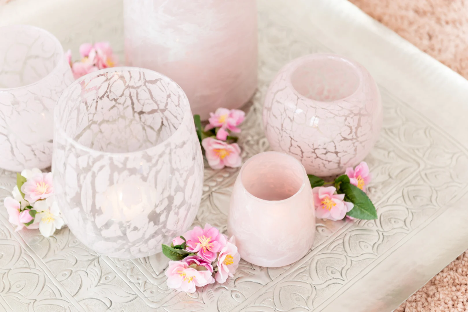 De Theelichthouder Rosa Glas Roze Groot staat op een decoratief zilveren dienblad, geaccentueerd met kleine roze bloemen en groene blaadjes.