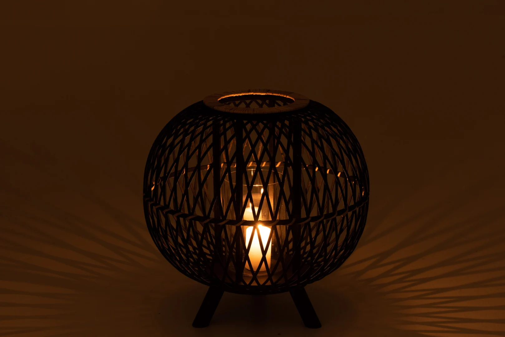 De Kaarsenhouder Bamboe Zwart Natuurlijk Groot is een ronde, geweven kandelaar die warm licht en ingewikkelde schaduwen werpt op donkere oppervlakken.