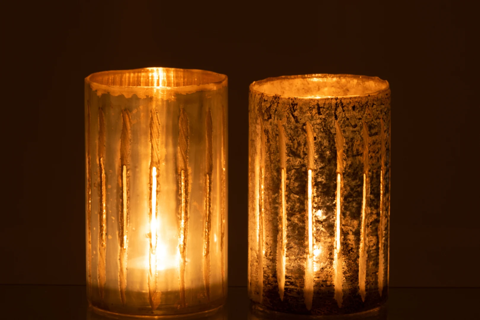 Set van twee grote blauwe glazen kandelaars van Theelichthouder Streep, elk met verticale gouden strepen en een warme, zachte gloed tegen een donkere achtergrond.