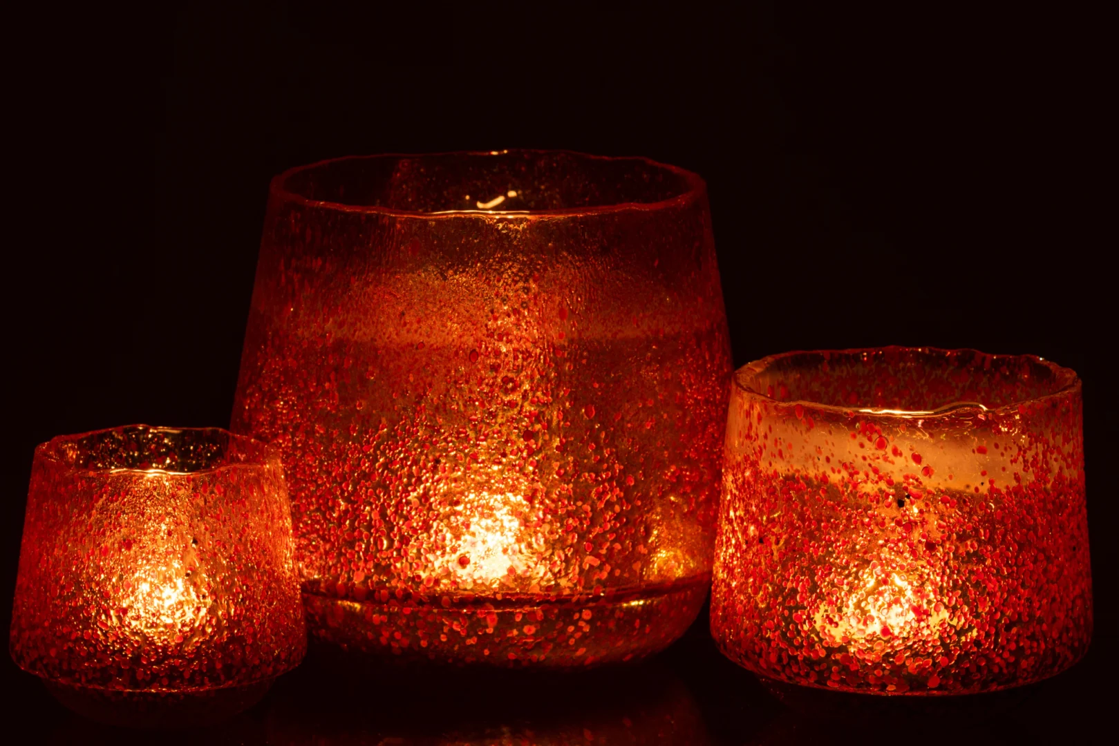 De Theelichthouder Stippen Glas Oranje Groot is een grote oranje glazen kandelaar met een gestructureerd, gespikkeld ontwerp dat een warme, zachte gloed uitstraalt wanneer hij brandt.