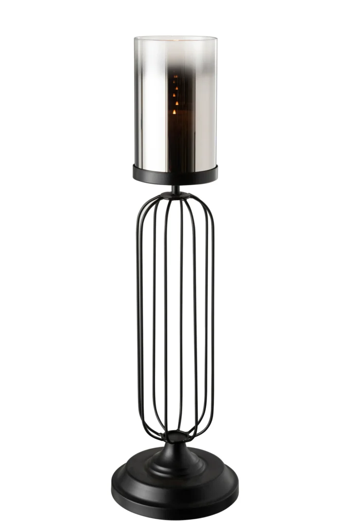 De Kaarsenhouder Orkaan Glas Zwart Groot is een moderne kandelaar van zwart metaal met een cilindrische glazen kap en een open, kooiachtige basis, die een warme gloed verspreidt wanneer hij brandt.