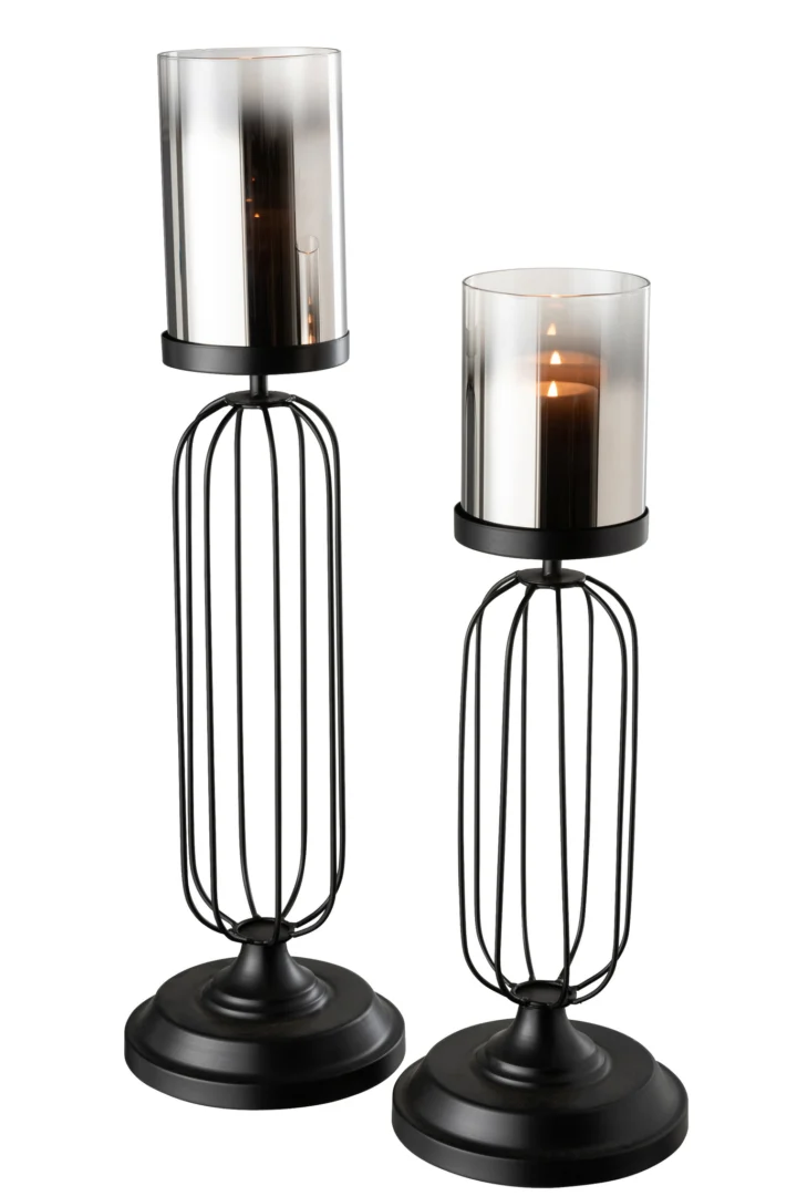 De Kaarsenhouder Orkaan Glas Zwart Groot is een zwart metalen kandelaar met een ronde basis, draadframeontwerp en een rokerig cilindervormig glazen deksel, perfect om een brandende kaars in te bewaren.