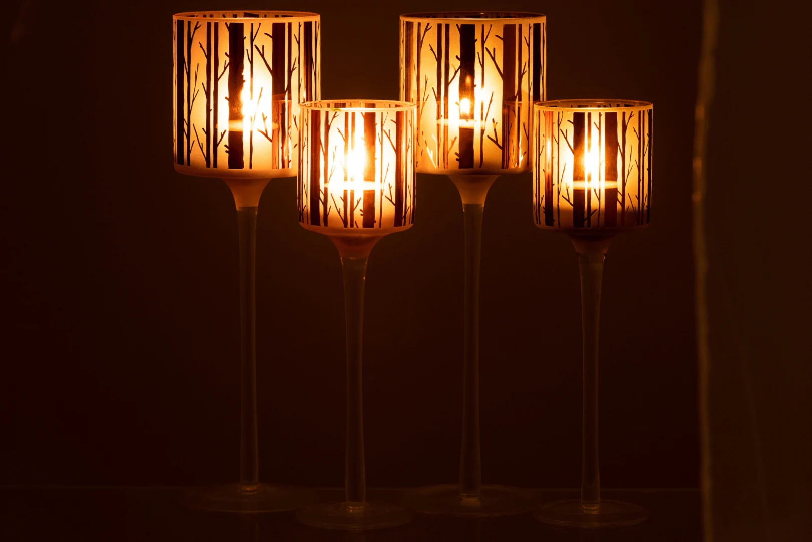 Theelichthouder Op Voet Boom Glas Bruin Groot Set 2 heeft twee hoge glazen kandelaars met boomtakpatronen, die een warme gloed verspreiden en een gezellige, elegante sfeer creëren in elke schemerige ruimte.