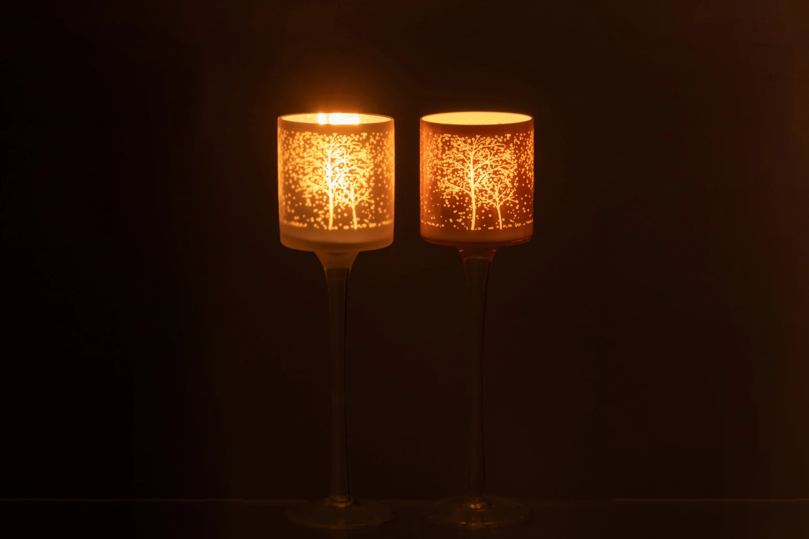 Theelichthouder Op Voet Boom Glas Wit Zalm Klein Set 2: Twee glazen kandelaars met boommotieven werpen een warme gloed als ze branden, waarbij de ingewikkelde patronen in de witte en zalmkleurige afwerking goed uitkomen.