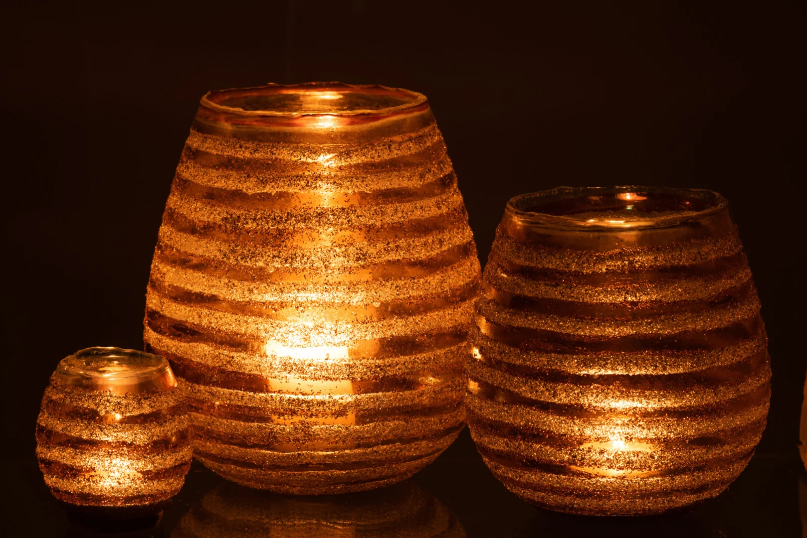 Theelichthouder Streep Rond Glas Bruin Groot is een grote, ronde glazen kandelaar met bruin en goud gestreepte accenten die een warme, uitnodigende gloed uitstraalt wanneer hij brandt.