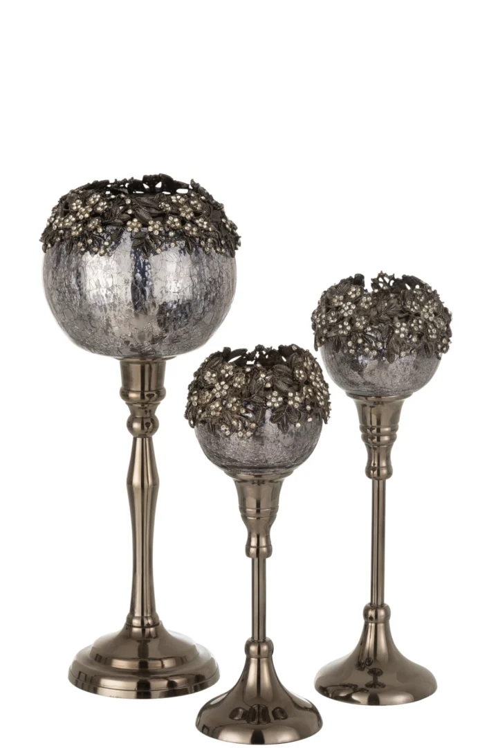 Theelichthouder Op Voet Juweel Glas Smokey Grijs Groot: een decoratieve zilveren kandelaar met een gestructureerd smokey grey glazen kopje en metallic bloemversieringen bovenop, afgebeeld tegen een witte achtergrond.