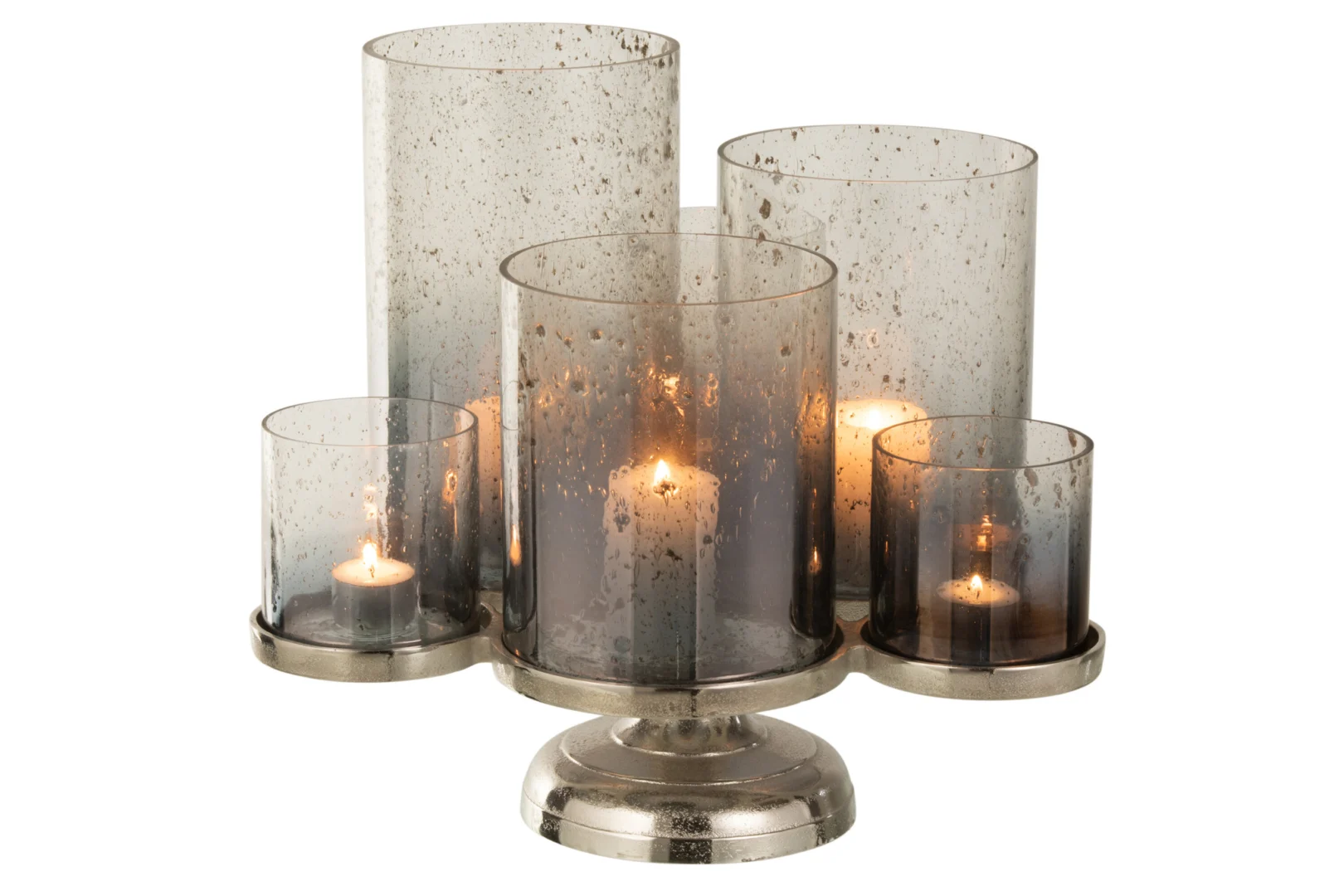 De Kaarsenhouder Orkaan Op Voet Glas Zilver Grijs heeft vijf pilaarkaarsen in rokerige, gespikkelde glazen houders van verschillende hoogten op een metalen voet; drie kaarsen branden, waardoor een warme gloed ontstaat door het zilvergrijze glas.