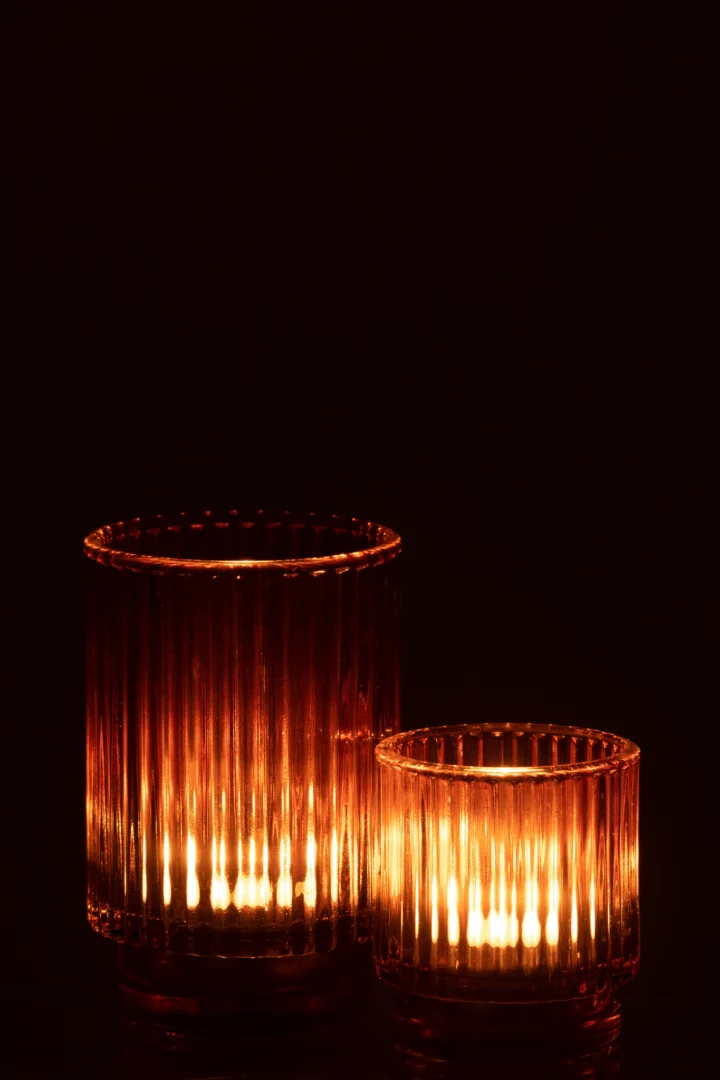 De Theelichthouder Gestreept Glas Bruin Groot gloeit warm in het donker en werpt zachte, verticale lichtpatronen door het geribbelde bruine glas.