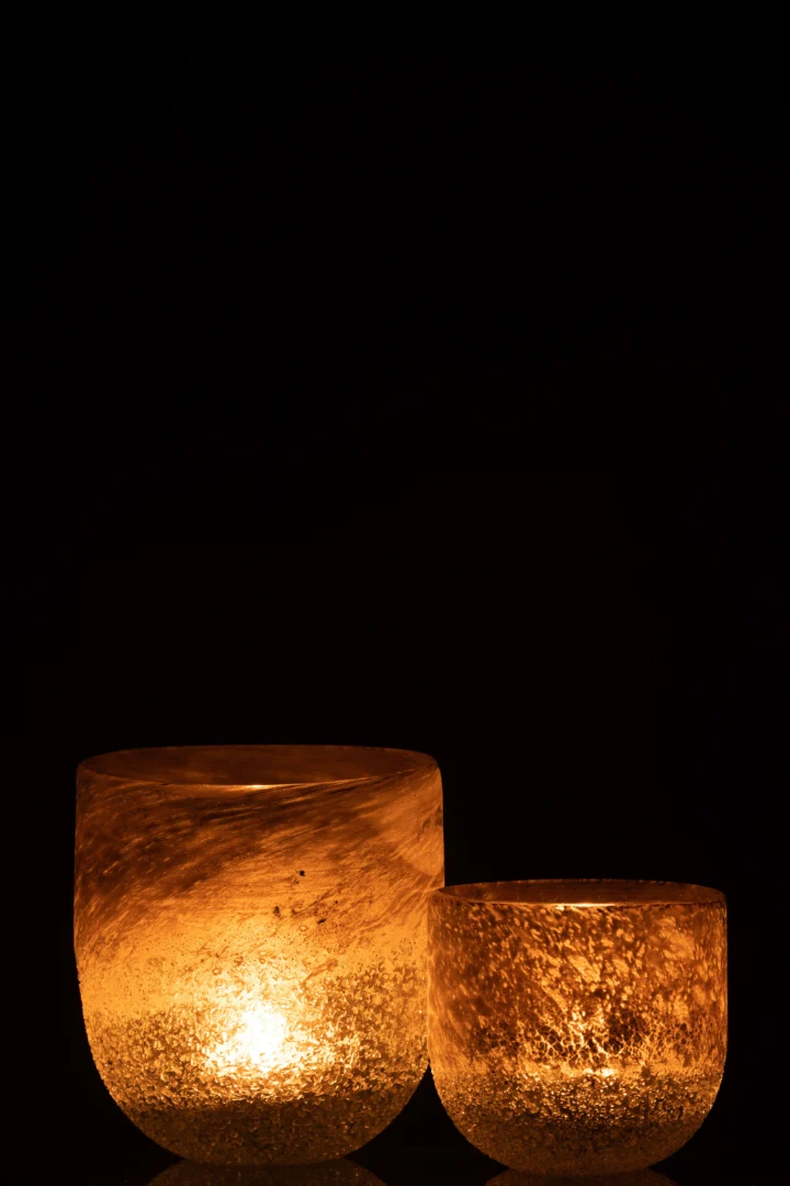 De Kaarsenhouder Orkaan Scavo Glas Grijs Groot straalt een warme gloed uit met zijn gestructureerde glazen oppervlak en creëert een gezellige sfeer tegen een donkere achtergrond. Het grotere formaat zorgt voor een uitnodigende en intieme sfeer.