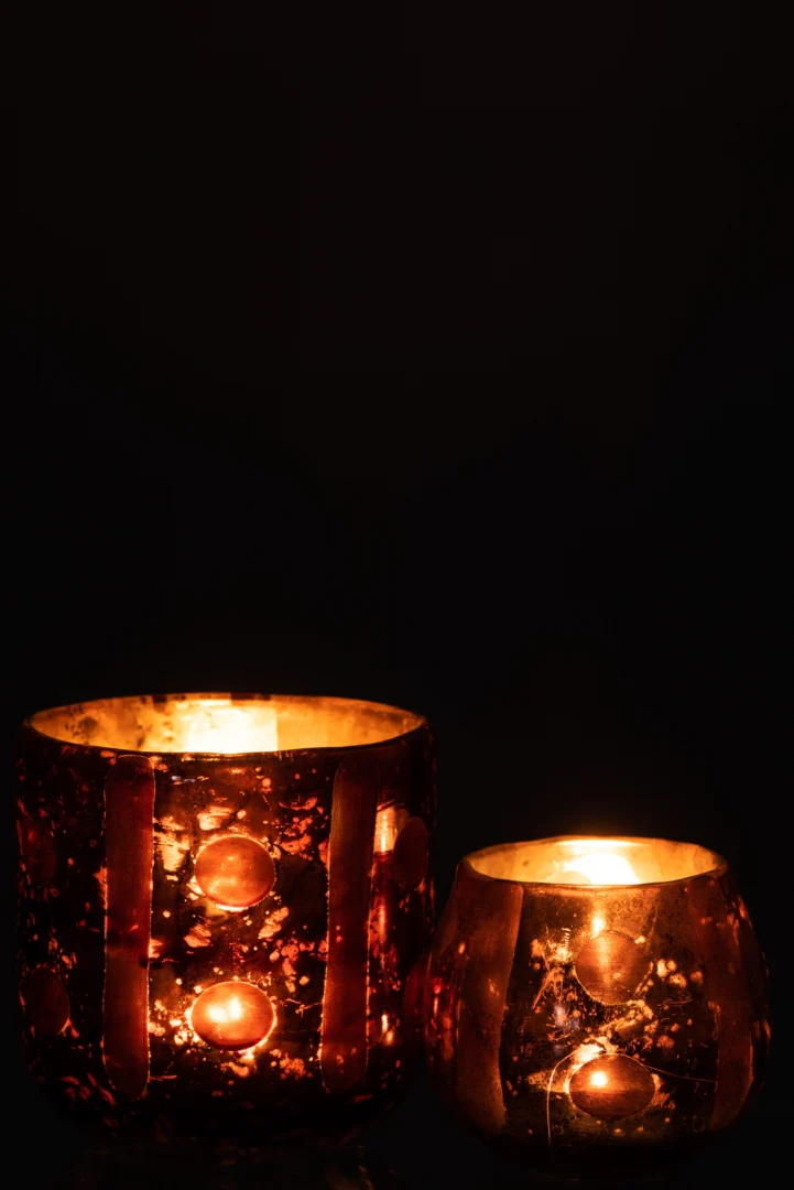 Twee Theelichthouder Kokosnoot Cilinder Glas Bruin kandelaars met gouden en roodachtige patronen gloeien warm op in het donker en creëren een gezellige, intieme sfeer als het licht door hun decoratieve glas weerkaatst.