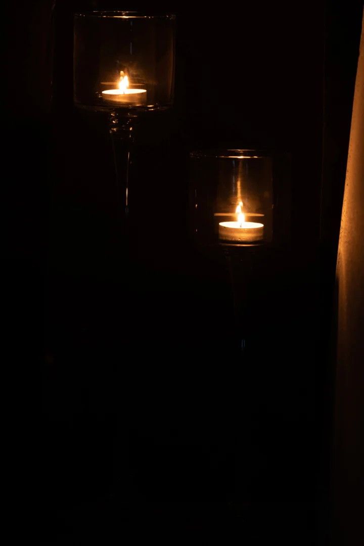 Twee kandelaars van Orkaan Te Voet Glas Transparant Groot gloeien warm op in het donker, werpen zacht licht en creëren een kalme, intieme sfeer.