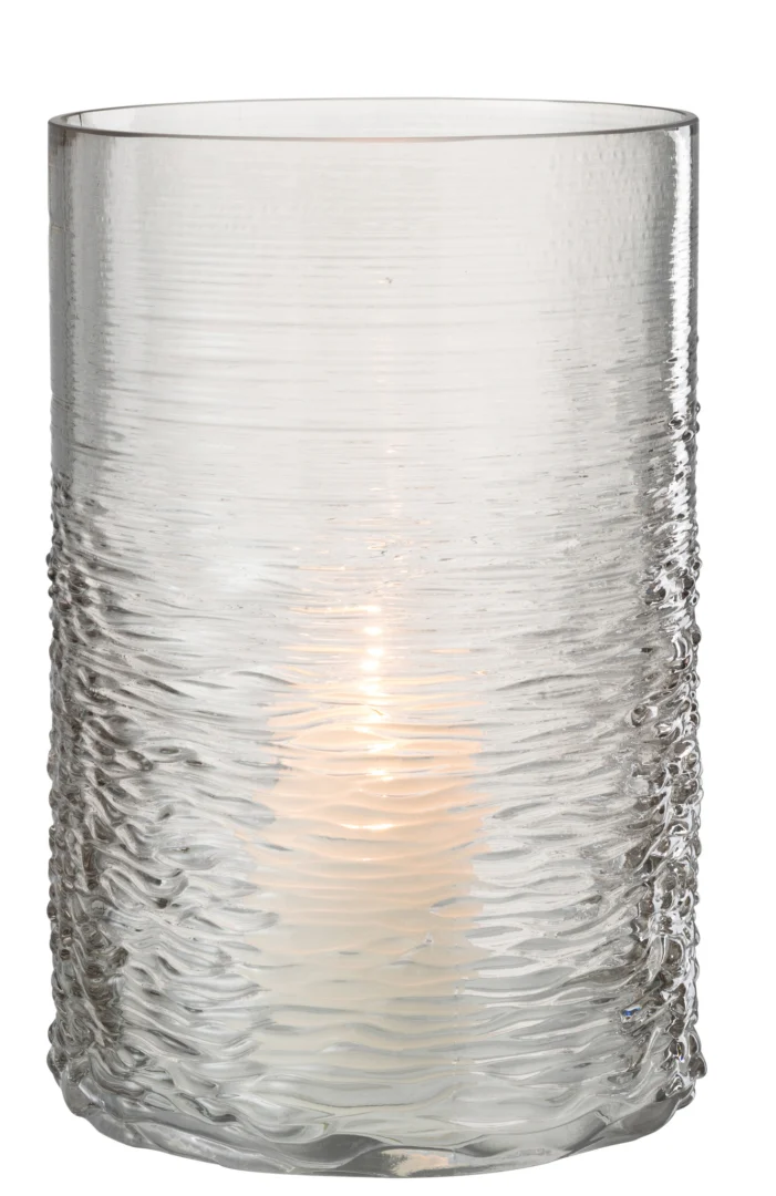 De Kaarsenhouder Orkaan Zeeglas Grijs Groot heeft helder getextureerd glas dat zacht gloeit als er een kaars in brandt, waarbij het licht door het golvende oppervlaktepatroon glinstert.