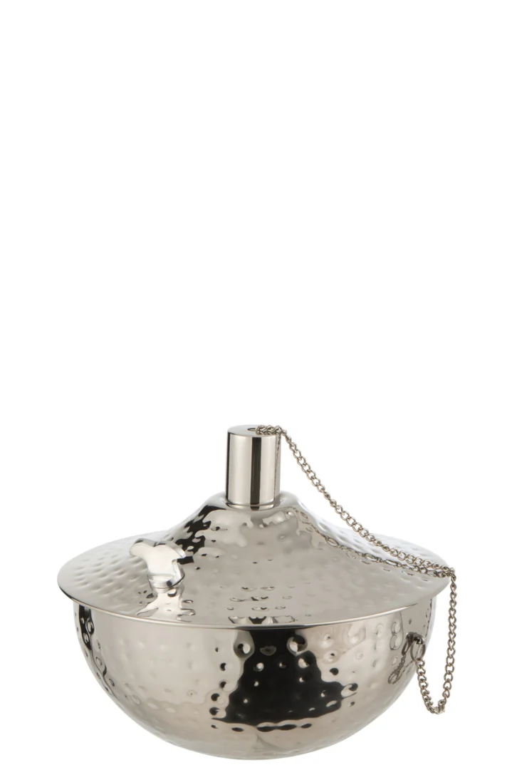 De Olielamp Roma RVS Zilver is een ronde, metalen olielamp met een gehamerde, glanzende afwerking, een bolle deksel met een klein handvat aan de bovenkant en een ketting aan de deksel.