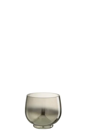 Een kleine, ronde glazen theelichthouder met de naam "Theelichthouder rond glas rook grijs/zilver klein," met een gladde, lichtgrijs getinte afwerking en een minimale basis, is leeg en gecentreerd afgebeeld op een effen witte achtergrond.