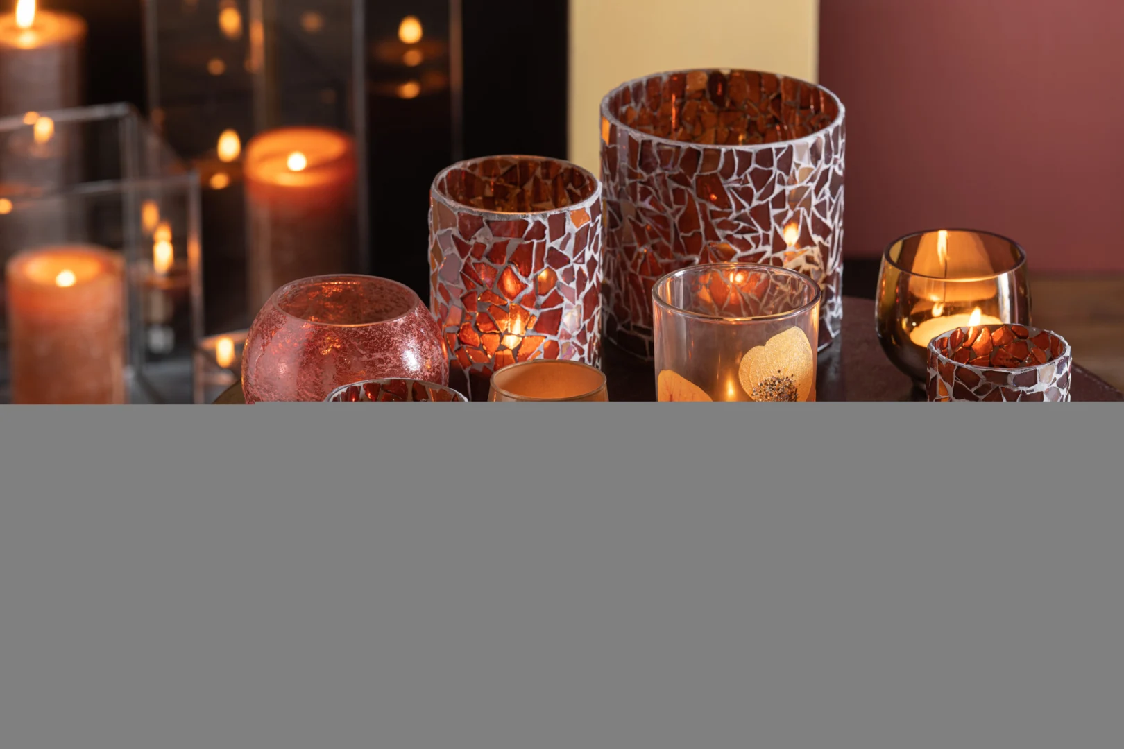 Een groep brandende Theelichthouder Mozaïekglas Bruin Klein kaarsen in mozaïek glazen houders met warme bruine tinten, die een gezellige en uitnodigende sfeer creëren.
