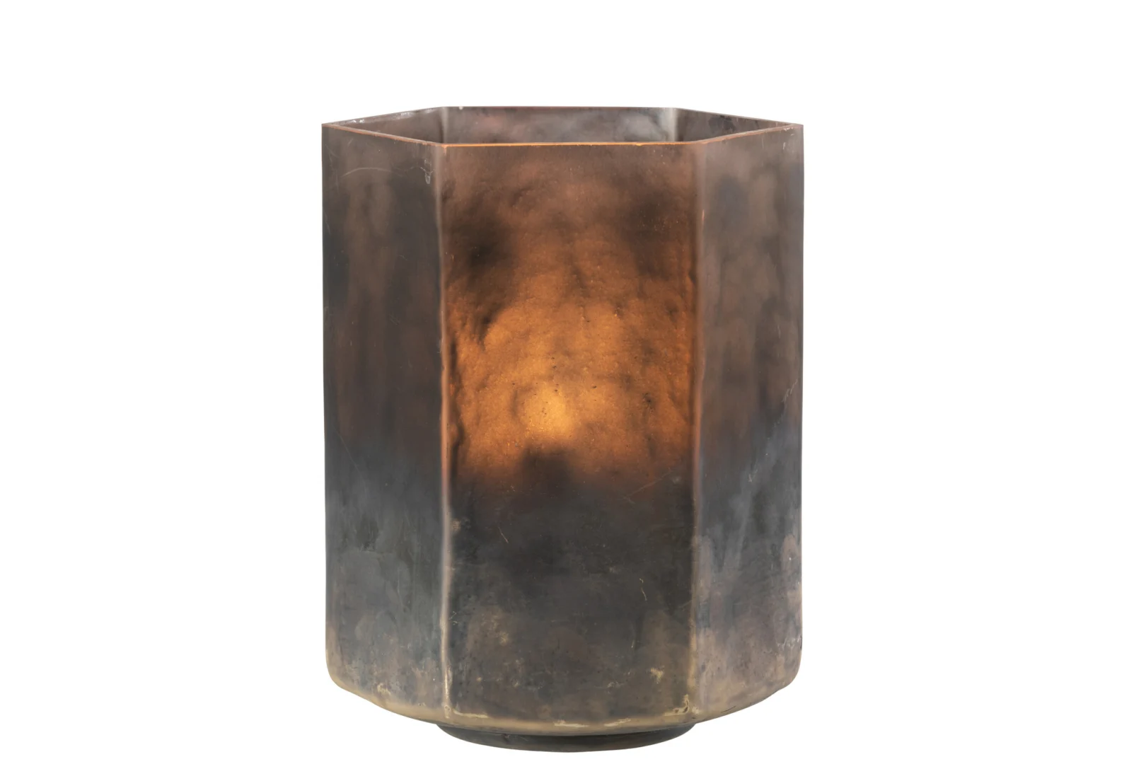 De Kaarsenhouder Orkaan Hexagoon Glas Grijs Groot is een grote, zeshoekige kandelaar van grijs glas met een brandende kaars erin, die een warme amberkleurige gloed verspreidt door het licht mistige, gestructureerde oppervlak. Tegen een effen witte achtergrond.