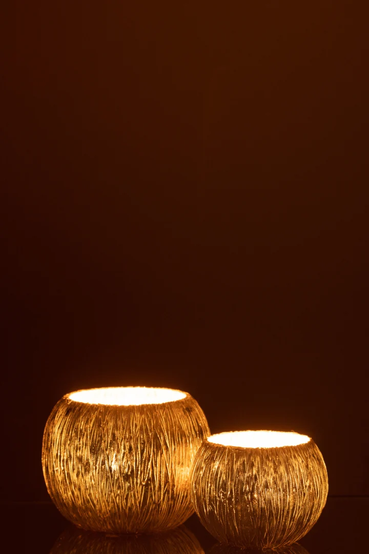 Twee Kaarsenhouder Hurricane Glas Zilver Klein kandelaars met gloeiende lichtjes binnenin zitten naast elkaar tegen een donkerbruine achtergrond en creëren een warme en gezellige sfeer.