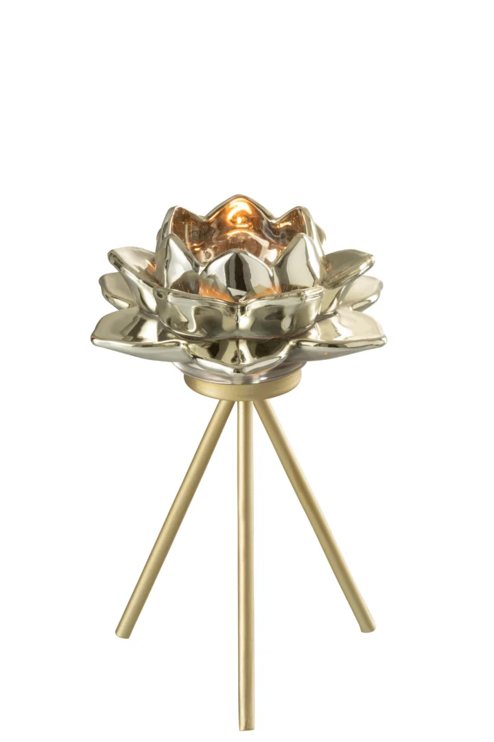 De Theelichthouder Op Voet Bloem Glas Grijs Klein, een lotusvormige kandelaar met een glanzende afwerking, staat op een driepotige gouden voet en houdt een kleine brandende kaars vast, tegen een effen witte achtergrond.