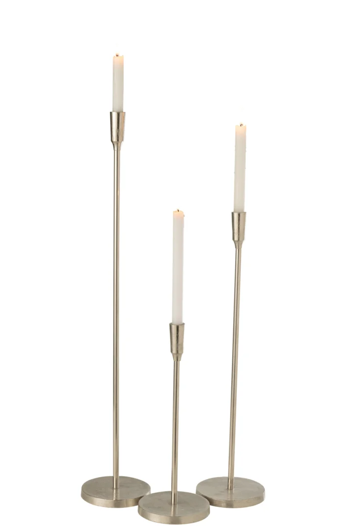 De Kandelaar Metaal Zilver Groot bestaat uit drie hoge zilvermetalen kandelaars van verschillende hoogtes, elk met een brandende witte conische kaars, rechtopstaand tegen een effen witte achtergrond.