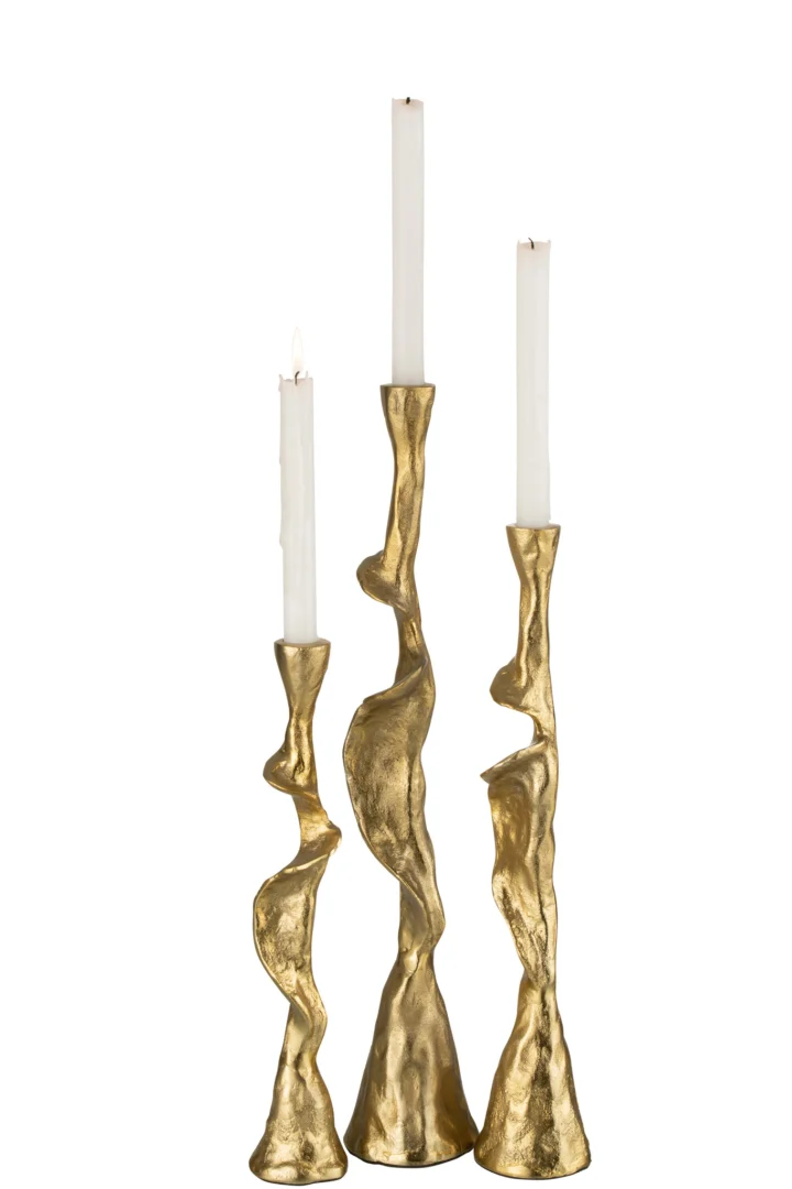 De Kaarsenhouder Ozy Aluminium Goud Set 3 bestaat uit drie gouden, sculpturale kandelaars in verschillende hoogtes met een gestructureerde afwerking en organisch ontwerp, elk voorzien van een witte conische kaars. Een van de kaarsen brandt tegen een effen witte achtergrond.