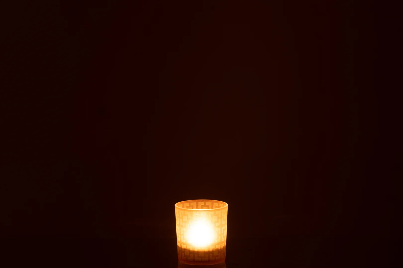 De Theelichthouder Vierkant Glas Beige Klein gloeit warm in de duisternis, het zachte kaarslicht creëert een kalme en serene sfeer.