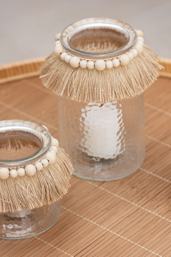 Twee Theelichthouder Kralen Glas Transparant Klein houders met beige raffia franje en houten kralenrand staan op een bamboematje; één houder heeft een witte kaars.