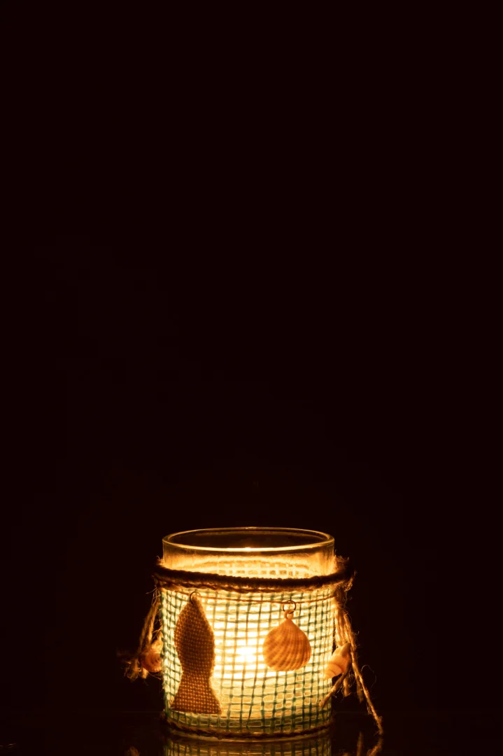 De Theelichthouder Zeedecoratie Glas Blauw/Wit gloeit warm in het donker, de blauw-witte glazen pot is versierd met jute, touw en kleine schelpen voor een charmante kustlook.