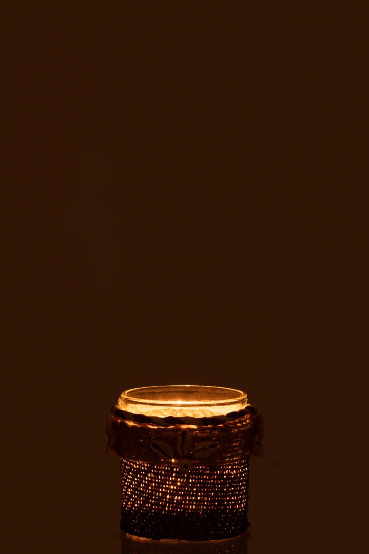 De Theelichthouder Schelpen Glas Bruin gloeit zacht met een brandende kaars en werpt een warm, vredig licht tegen een donkerbruine achtergrond voor een gezellige sfeer.