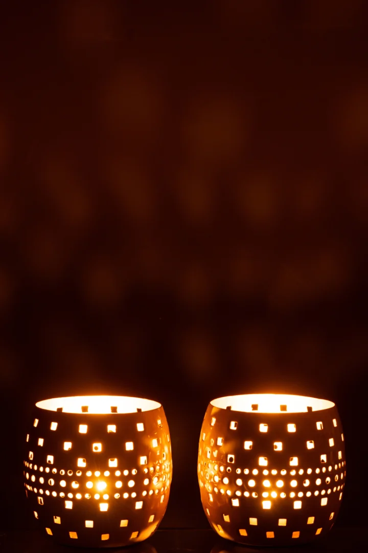 De Kaarsenhouder Metaal Geperforeerd Lichtroze Beige Set van 2 verspreidt een warm licht door de geperforeerde patronen, waardoor sfeervolle schaduwen op de achtergrond ontstaan.