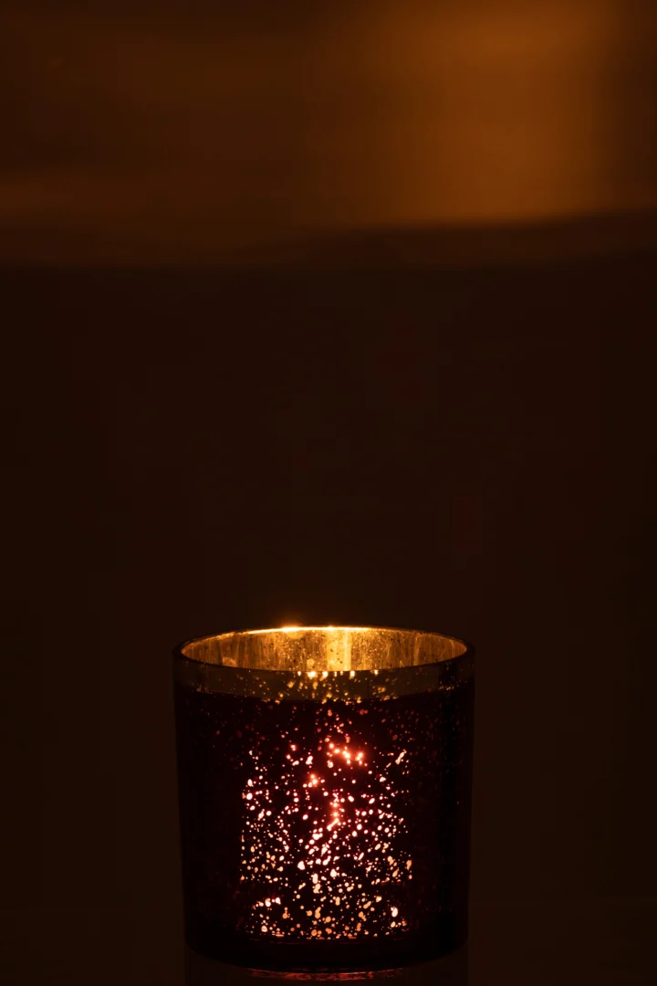 De Kaarsenhouder Orkaan Gouden Rand Glas Bourgondië Groot werpt een warm, gloeiend licht door het donkere glas met kleine perforaties, waardoor er in een schemerige kamer stippelreflecties ontstaan op nabije oppervlakken.